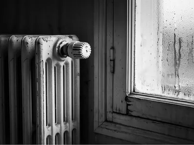 Radiateur en fonte près d’une fenêtre couverte de condensation